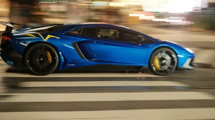 A blue sports car driving down a city street